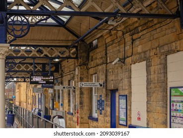 Malton, UK.  December 14, 2021.  A small town and country railway station concourse.  There is a number of signs and notices on the walls. An ornate canopy is overhead.