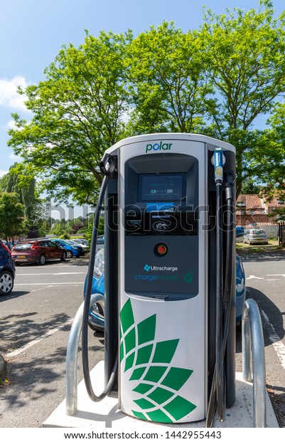 Malton, UK.\
June 28, 2019. Charging point for electric vehicles situated in a\
car park.  Its Green credentials are emphasised by the green leaves\
of a tree against which it is\
set.