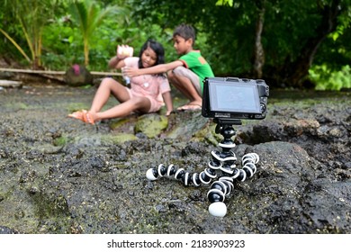 Maluku, Indonesia - January 5, 2021: Children Playing In A Small Water Pool On A Rock While Being Recorded By A Camera