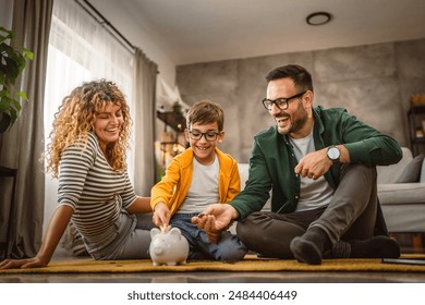 mam dad and son sit on the carpet,floor and save money in the piggy bank at home