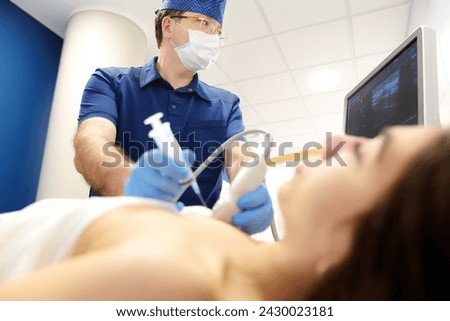 Mammalogist doctor examines a woman breasts and lymph nodes during appointment. Skillful oncologist puncture of mammary glands of young patient under review ultrasound for diagnosis of breast cancer.