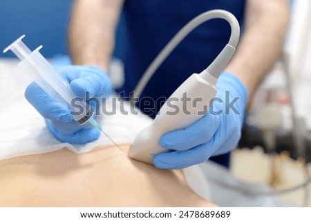 Mammalogist doctor examines a woman breasts and lymph nodes during appointment. Skillful oncologist puncture of mammary glands of young patient under review ultrasound for diagnosis of breast cancer.