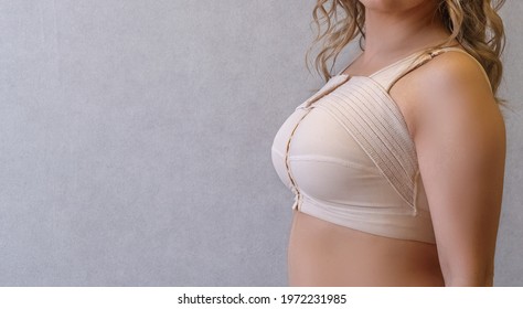 mammoplasty Young woman in beige compression bra bandage after breast augmentation surgery mammoplasty. banner. advertising. copy space