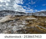 Yellowstone’s Mammoth Hot Springs on a crisp morning, showcasing intricate limestone terraces and geothermal pools. The mineral-rich formations and mist create an otherworldly landscape.