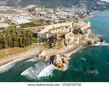 Mamure Castle or Mamure kalesi is a medieval castle in the Anamur district of Mersin Province, Turkey. Aerial view of castle, sea, mountains and numerous greenhouses