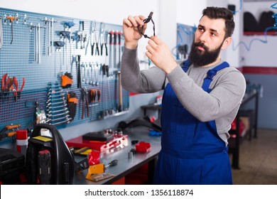 Man 25-35 years old is observing motorbike part for fixing in workshop.  - Shutterstock ID 1356118874