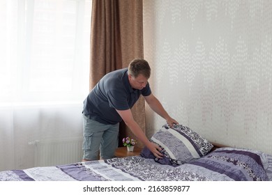 Man 40-44 Years Old In Home Clothes Makes The Bed Morning.