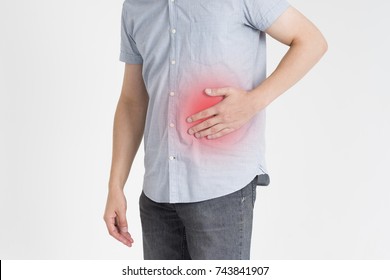 Man with abdominal pain, stomach ache on gray background, with red dot