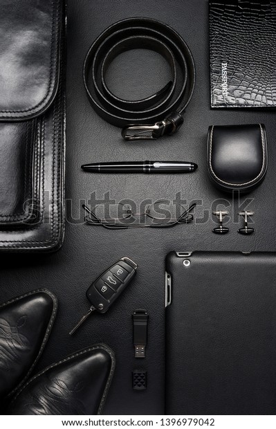 Man accessories\
in business style, briefcase, gadgets, shoes, clothes and other\
luxury businessman attributes on leather black background, fashion\
industry, top view 