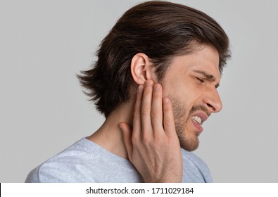 Man With Ache Holding Ear Isolated On Gray Background