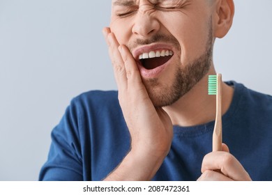 Man With Aching Teeth And Brush On Grey Background