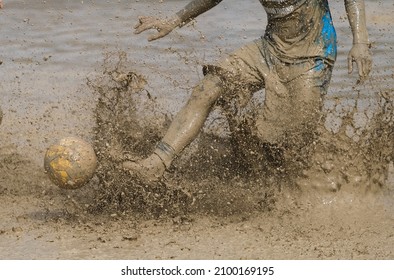 A Man In Action, Dribling The Ball During Muddy Football Competition.