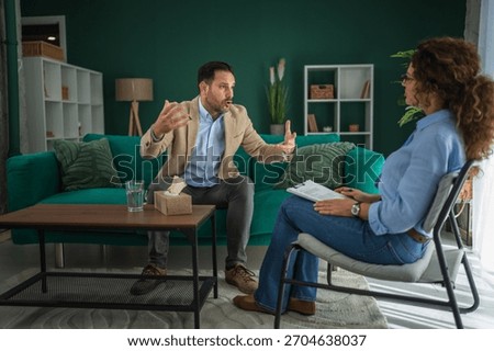 Man actively talking and gesticulating, expressing his feelings and frustrations to a female psychotherapist during a therapeutic session, seeking conflict resolution and stress management