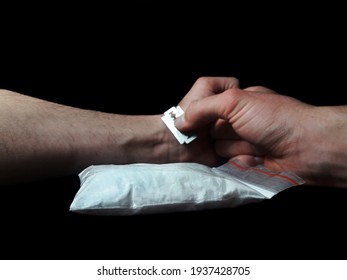 Man addicted to cocaine cuts veins on a hand, man in depression trying to commit suicide with razor blade and cocaine drug powder bag on black table