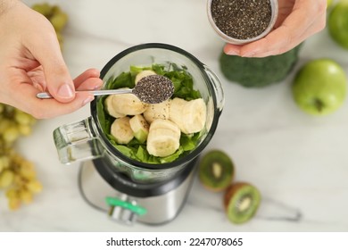 Man adding chia seeds into blender with ingredients for smoothie at table, above view - Powered by Shutterstock