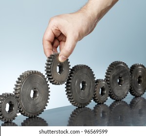 Man adding a cog gear in a row of old cog gears.