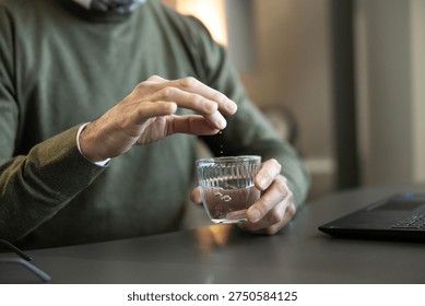 Man adding crumbling effervescent tablet into glass of water. Dissolving medicine for healthcare, wellness, and symptom relief