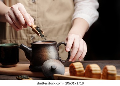 Man Adding Dried Green Tea Leaves In Ceramic Pot When Preparing Drink For Mid Autumn Festival