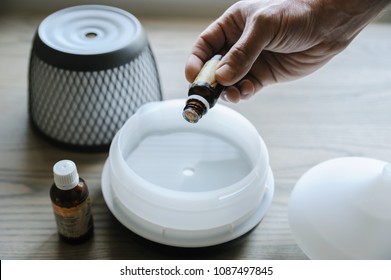 A man is adding essential oil to an aroma diffuser.