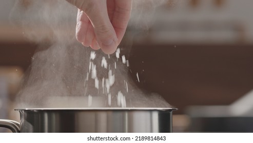 Man Adding Salt To Boiling Water In Saucepan, Wide Photo