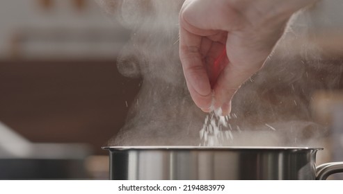 man adding salt to boiling water in saucepan, wide photo - Shutterstock ID 2194883979
