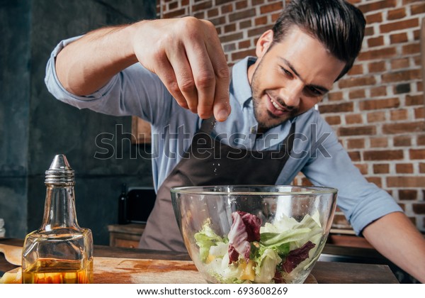 man adding salt into fresh\
salad