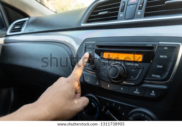 The man adjust car radio\
to FM mode.