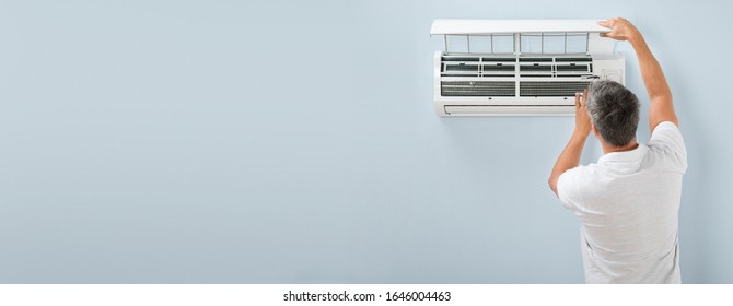 Man Adjusting Air Conditioning System At Home