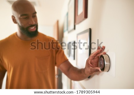 Man Adjusting Digital Central Heating Thermostat At Home Foto stock © 