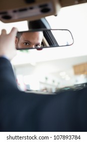 Man Adjusting A Rear View Mirror While Sitting In A Car