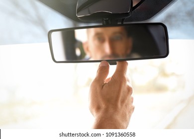 Man Adjusting Rear View Mirror In Car