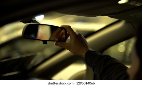 Man adjusting rear view mirror in car, driving license exam, visibility range