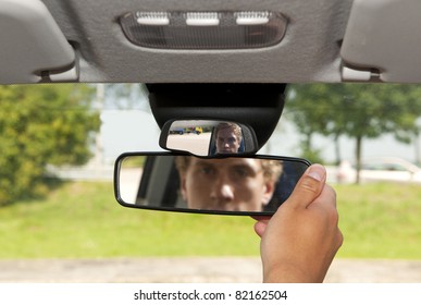 Man, Adjusting The Rear View Mirror Of His Car