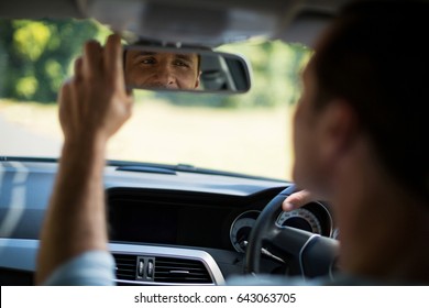 Man Adjusting Rearview Mirror In Car