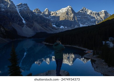 Man admiring Moraine Lake at sunrise from the top of the mountain, with the snow-capped mountains in the background. - Powered by Shutterstock