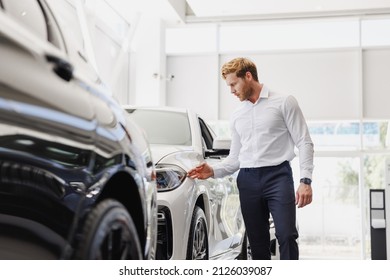Man adult customer male buyer client wears classic suit white shirt chooses auto wants to buy new automobile touch check car in showroom vehicle salon dealership store motor show indoor. Sales concept - Shutterstock ID 2126039087