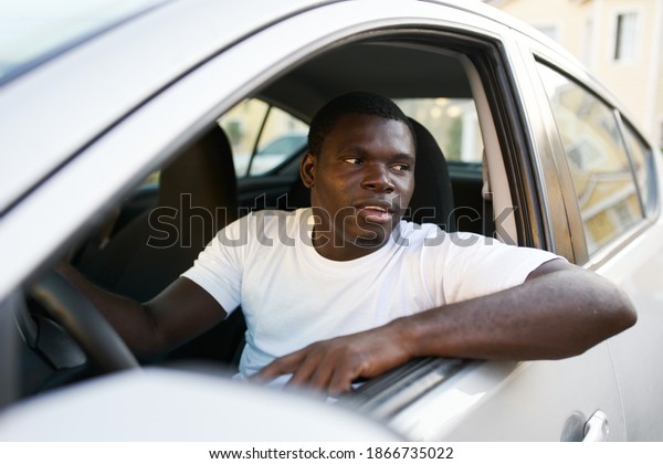 man of\
african appearance driving a car trip\
road