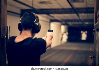 Man Aiming Pistol At Target In Indoor Firing Range Or Shooting Range