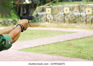 A Man Aiming Pistol At Target Out Indoor Firing Range Or Shooting Range. 9mm Automatic Pistol Gun Holding In Hand Of Gun Shooter, Training By Using Pistol Gun To Save And To Protect