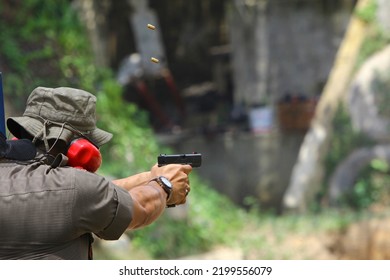 A Man Aiming Pistol At Target Out Indoor Firing Range Or Shooting Range. 9mm Automatic Pistol Gun Holding In Hand Of Gun Shooter, Training By Using Pistol Gun To Save And To Protect