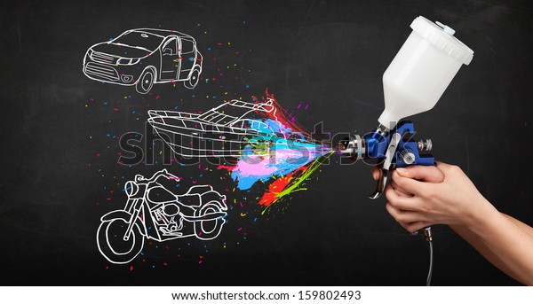 Man with airbrush spray paint with car,\
boat and motorcycle drawing on dark\
background