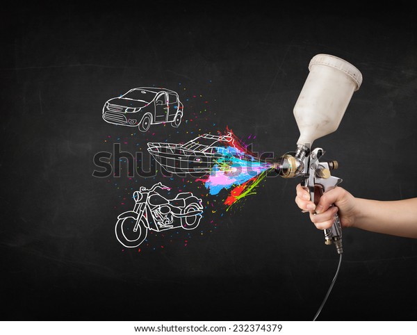 Man with airbrush spray paint with car,\
boat and motorcycle drawing on dark\
background