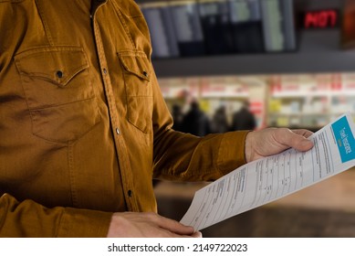 Man In Airport Holding Travel Insurance Claim Form For Filling