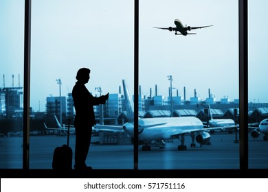 Man In Airport With Luggage And Checking Mobile Phone 