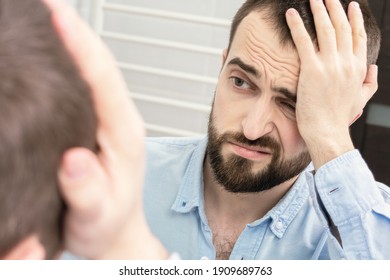 Man With A Alcohol Withdrawal Syndrome And A Headache Looks In The Mirror In The Morning, Portrait, Close-up