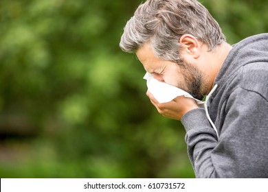 Man with allergy or an infection sneezing  - Shutterstock ID 610731572