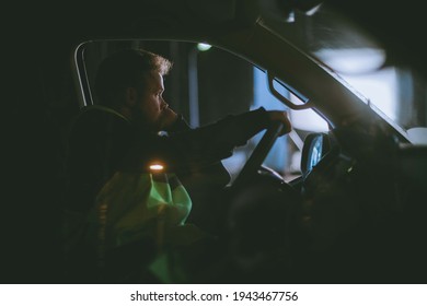 The Man Is Alone Driving A Car At Night. Young Serious Focused Guy Is Driving In A Car Driving Late At Night In The Dark