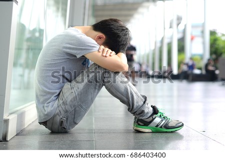 Man alone sitting in the corner strained unhappy depressed, destroyed, wasted and sad suffering 