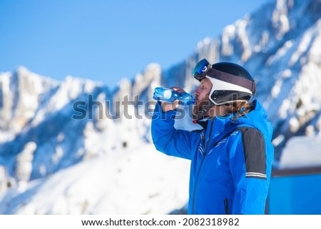 Man alpine skier drink fresh water from bottle Dolomities Italy in winter beautiful alps winter mountains and ski slope Cortina d'Ampezzo Faloria skiing resort area