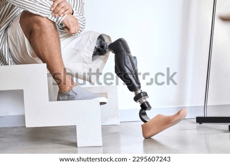 Man amputee with prosthetic leg disability on above knee transfemoral leg prosthesis artificial device sitting on stairs, close up. People with amputation disabilities everyday life. 商業照片 © 